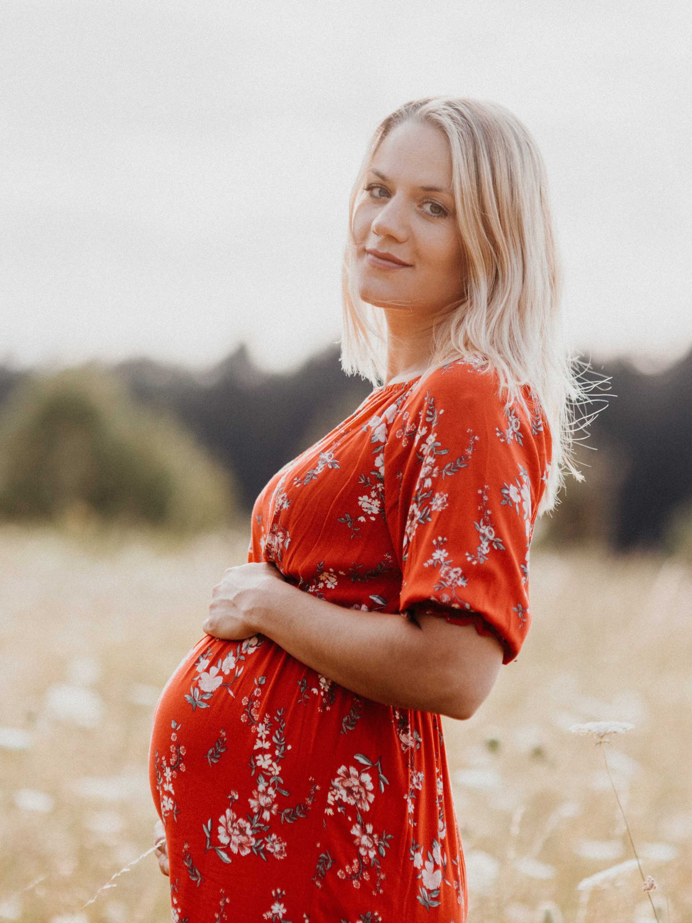 Schwangere Frau schaut glücklich in die Kamera - Momente des Schenkens | Emotionsbild