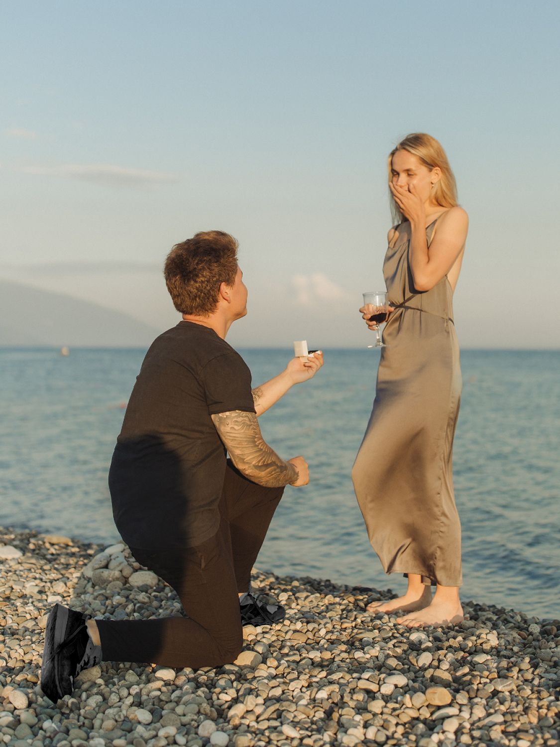 Mann macht bei romantischer Kullisse seiner Frau einen Hochzeitsantragt und zeigt ihr ihren Verlobungsring | Emotionsbild