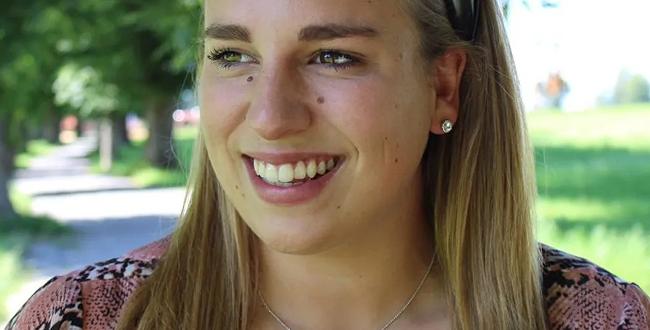 Lächelnde junge Dame trägt Ohrringe aus echtem Gold